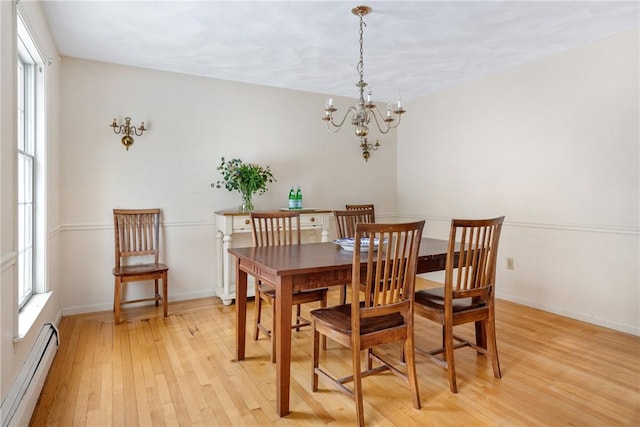 dining space featuring a baseboard heating unit, a notable chandelier, light hardwood / wood-style floors, and a healthy amount of sunlight