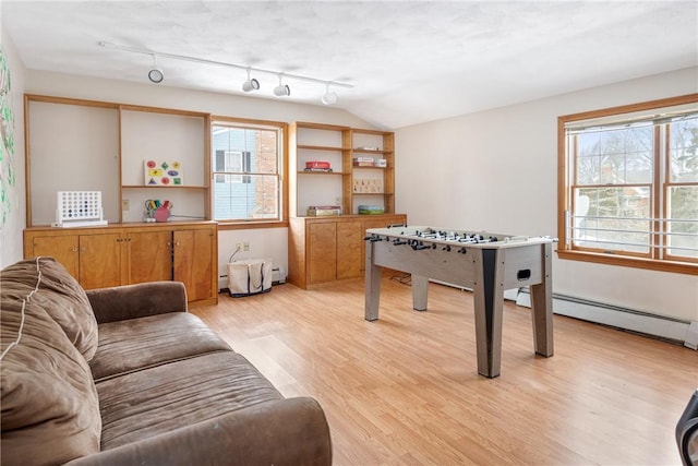 rec room with lofted ceiling, a baseboard heating unit, a wealth of natural light, and light hardwood / wood-style floors