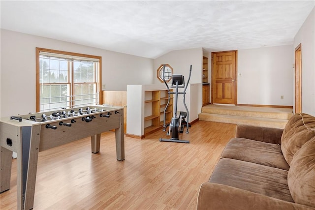 recreation room with vaulted ceiling, light hardwood / wood-style floors, and a textured ceiling