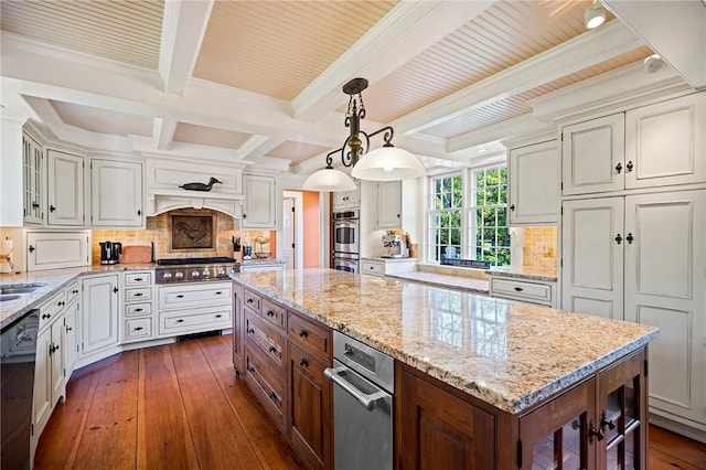 kitchen featuring appliances with stainless steel finishes, a kitchen island, dark hardwood / wood-style flooring, backsplash, and hanging light fixtures