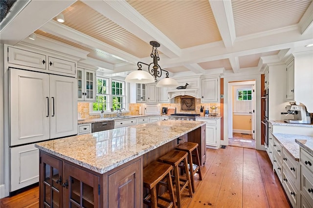 kitchen with white cabinets, a kitchen island, light stone countertops, and pendant lighting