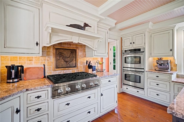 kitchen featuring light wood-type flooring, stainless steel appliances, beamed ceiling, and tasteful backsplash