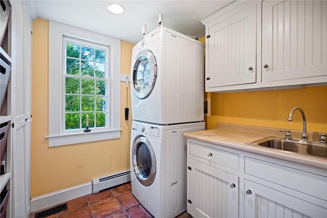 clothes washing area with stacked washer / dryer, a baseboard radiator, sink, and cabinets