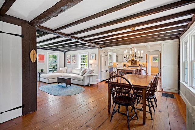 dining room featuring dark wood-type flooring, beamed ceiling, and a notable chandelier