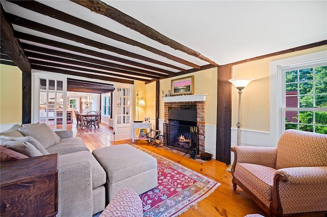 living room with hardwood / wood-style flooring, beamed ceiling, and a brick fireplace