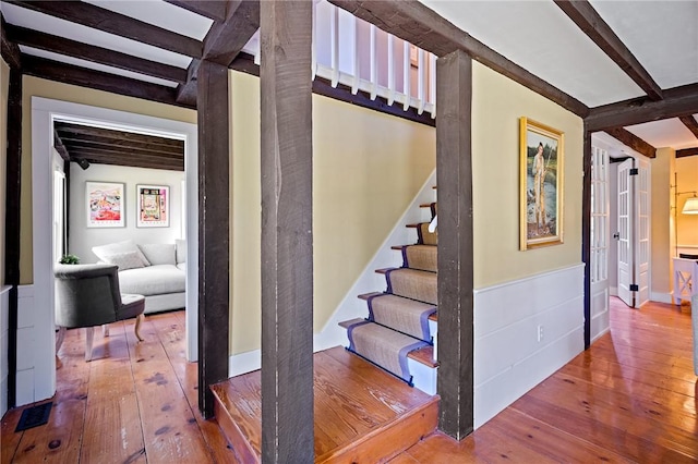 staircase with hardwood / wood-style flooring and beamed ceiling