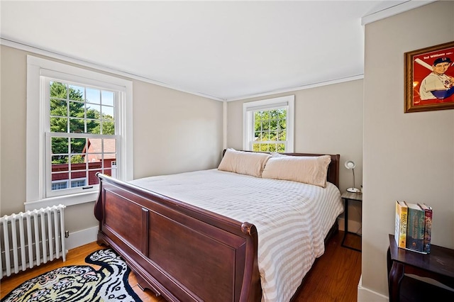 bedroom featuring hardwood / wood-style flooring, radiator heating unit, and multiple windows