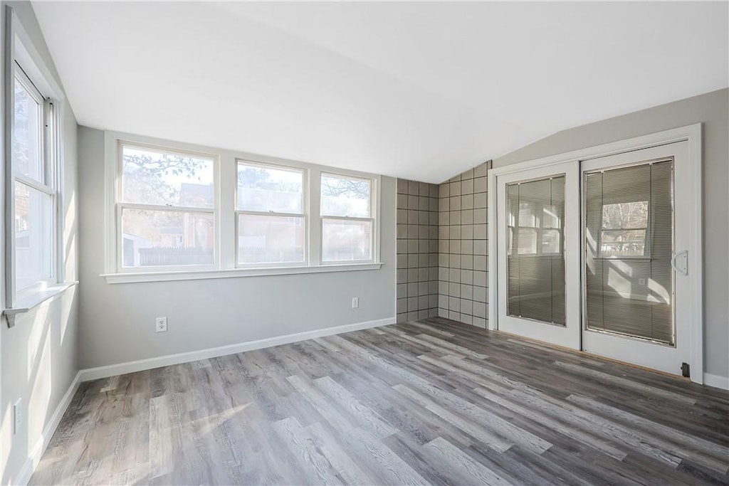 empty room with hardwood / wood-style floors and lofted ceiling