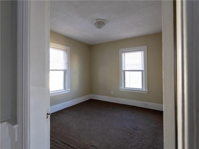 unfurnished room with dark carpet