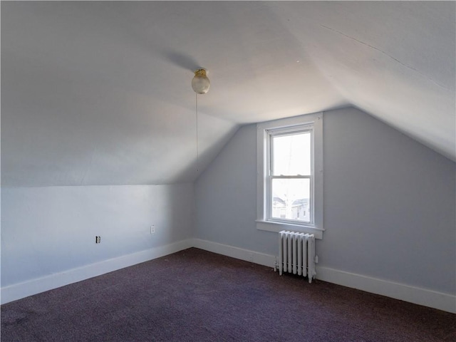 bonus room with radiator heating unit, vaulted ceiling, and dark colored carpet