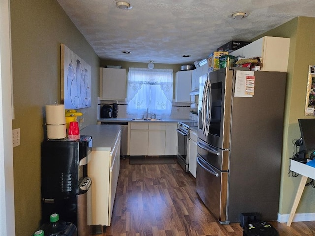 kitchen featuring sink, white cabinets, dark wood-type flooring, a textured ceiling, and stainless steel appliances