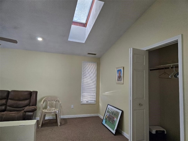 living area with ceiling fan, vaulted ceiling with skylight, and carpet