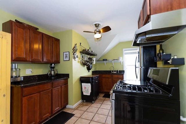 kitchen with light tile patterned floors, sink, stainless steel gas stove, ceiling fan, and lofted ceiling