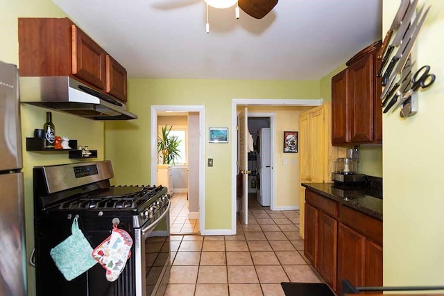 kitchen featuring ceiling fan, dark stone countertops, stainless steel appliances, and light tile patterned flooring