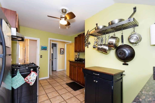 kitchen with vaulted ceiling, ceiling fan, light tile patterned floors, exhaust hood, and stainless steel appliances