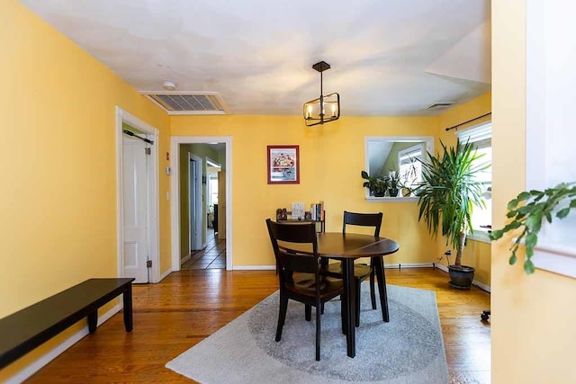 dining space featuring hardwood / wood-style floors and a notable chandelier