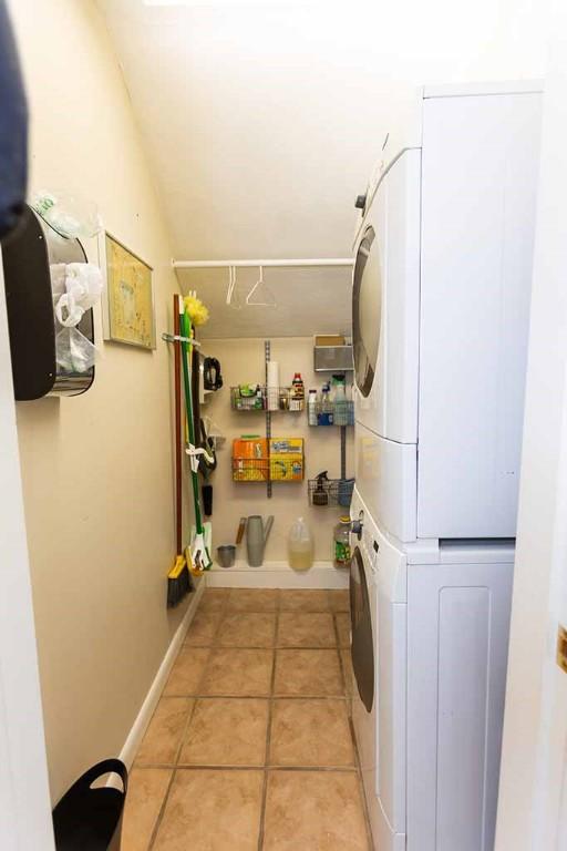 laundry room with stacked washing maching and dryer and light tile patterned floors