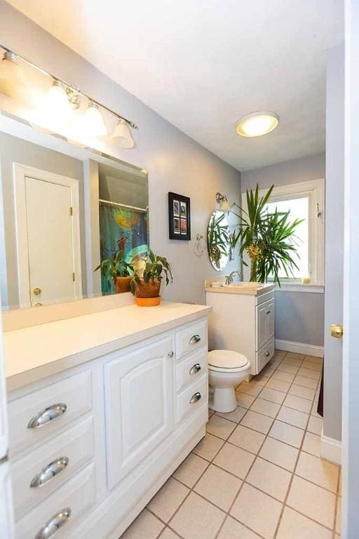 bathroom with vanity, toilet, curtained shower, and tile patterned flooring