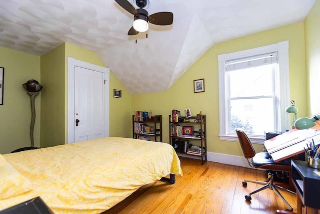 bedroom with a closet, ceiling fan, hardwood / wood-style floors, and vaulted ceiling