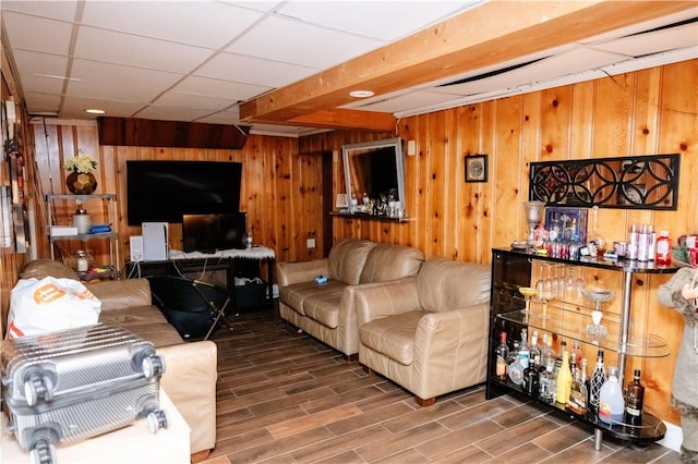 living room featuring bar, wood walls, and a paneled ceiling