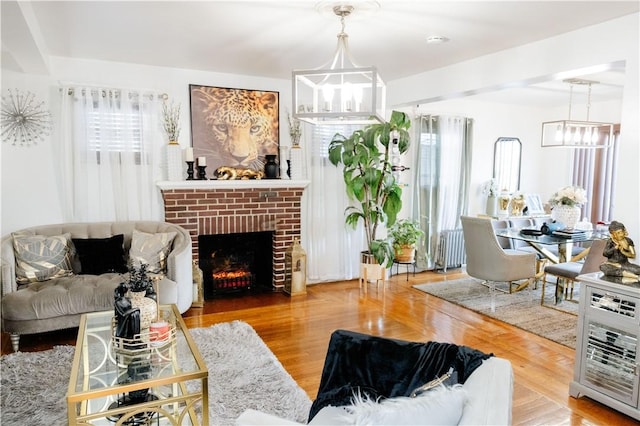 living room featuring a fireplace, radiator heating unit, a healthy amount of sunlight, and a notable chandelier