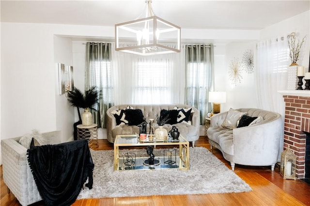 living room featuring an inviting chandelier, hardwood / wood-style floors, and a fireplace