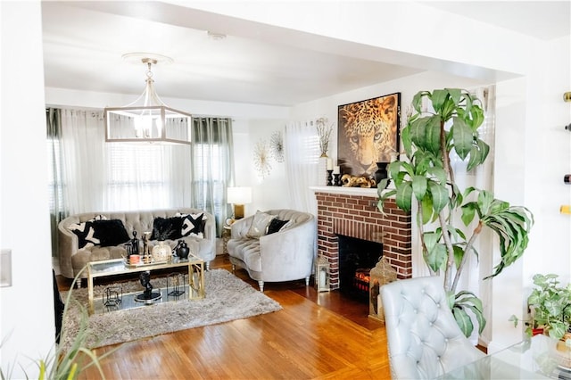 living room with a brick fireplace, hardwood / wood-style flooring, and an inviting chandelier