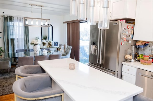 kitchen featuring white cabinets, stainless steel appliances, a wealth of natural light, and pendant lighting