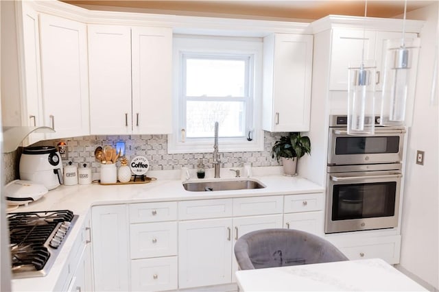 kitchen featuring sink, white cabinetry, hanging light fixtures, and appliances with stainless steel finishes