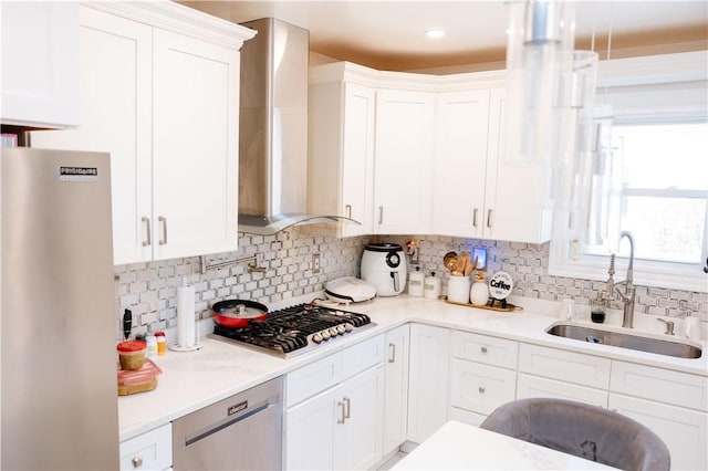 kitchen with white cabinets, appliances with stainless steel finishes, exhaust hood, sink, and backsplash