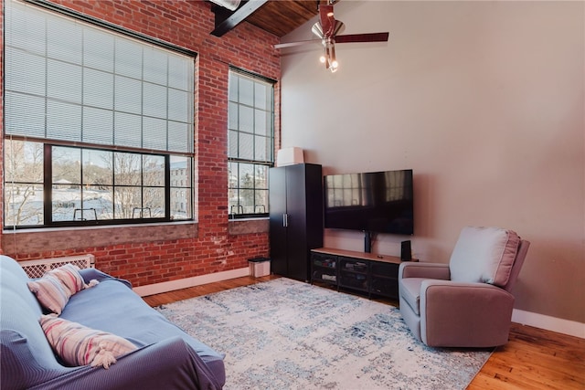 living room featuring beamed ceiling, brick wall, light hardwood / wood-style floors, and wooden ceiling