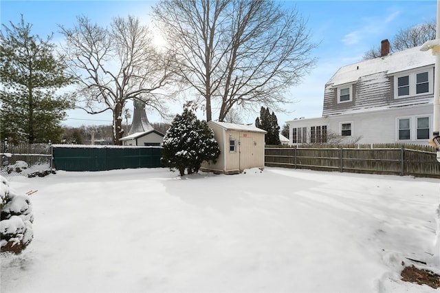 snowy yard featuring a storage unit