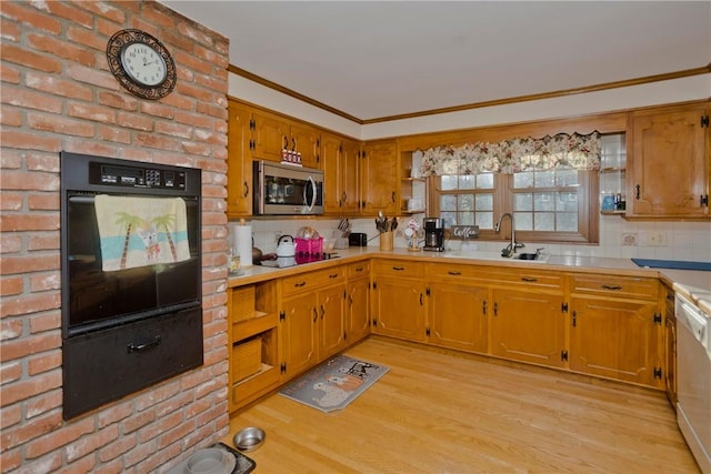 kitchen featuring dishwasher, black oven, sink, cooktop, and light wood-type flooring