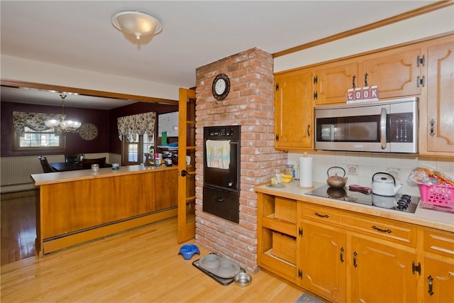 kitchen featuring baseboard heating, black appliances, tasteful backsplash, and hanging light fixtures