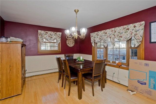 dining area with hardwood / wood-style flooring, a chandelier, and a baseboard heating unit