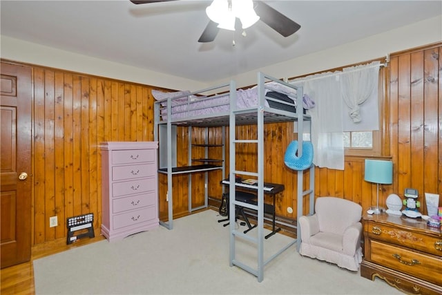 carpeted bedroom with ceiling fan and wooden walls