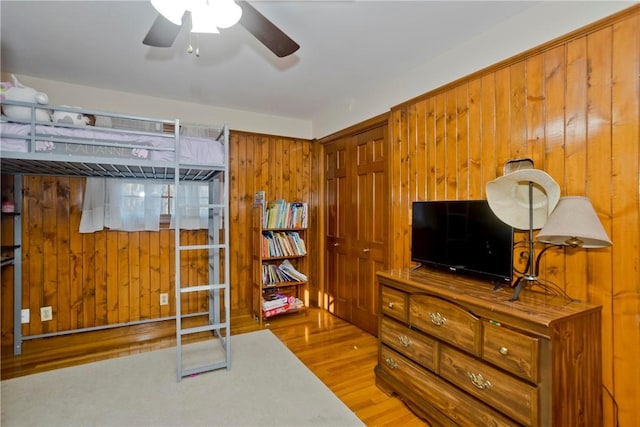 bedroom with wooden walls and light hardwood / wood-style flooring