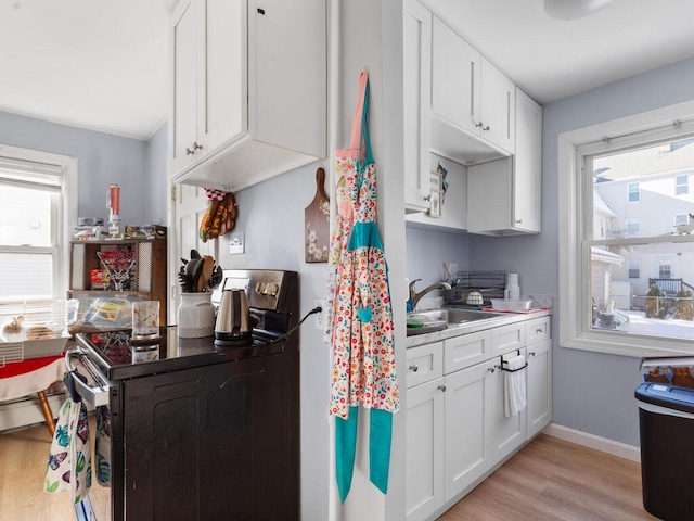 kitchen featuring white cabinetry, electric stove, sink, and light wood-type flooring