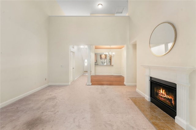 unfurnished living room with ornamental molding, a chandelier, a tile fireplace, and light carpet