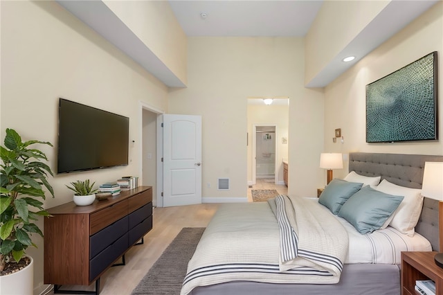 bedroom featuring connected bathroom and light hardwood / wood-style flooring