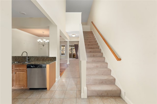 interior space featuring stainless steel dishwasher, pendant lighting, sink, light tile patterned floors, and a notable chandelier