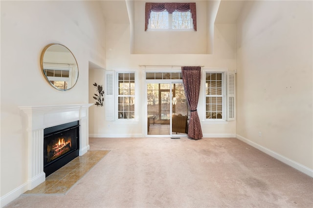 unfurnished living room with light carpet, a tile fireplace, and a towering ceiling