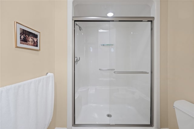 bathroom with toilet and a shower with door