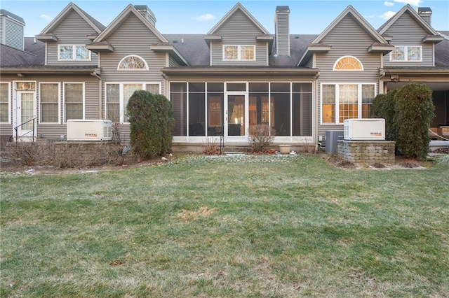 rear view of property featuring a sunroom and a lawn