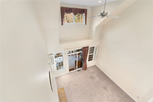 carpeted living room featuring a towering ceiling and ceiling fan