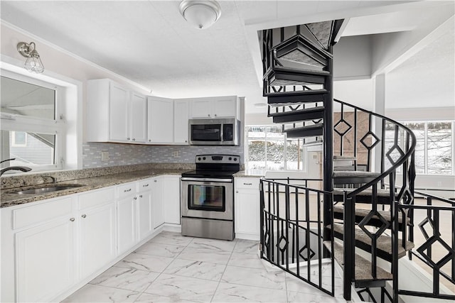 kitchen featuring tasteful backsplash, white cabinetry, sink, stainless steel appliances, and stone countertops