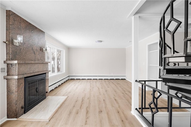 living area with a large fireplace, baseboards, light wood finished floors, and stairs