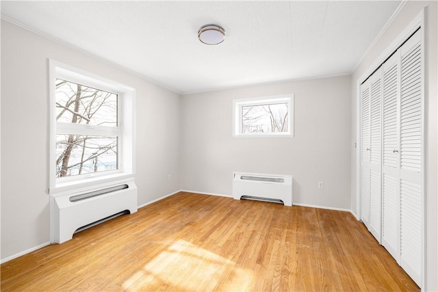 unfurnished bedroom with a closet, multiple windows, crown molding, and wood finished floors