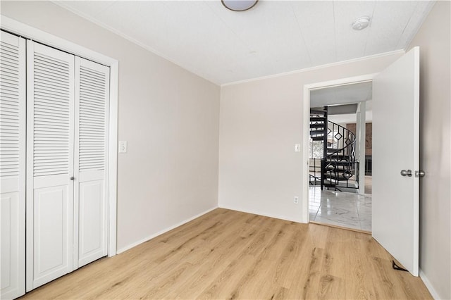 unfurnished bedroom with light wood finished floors, a closet, and crown molding