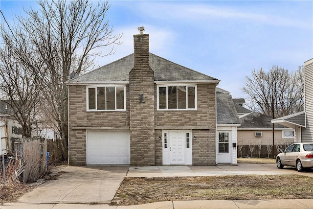 view of front of house with an attached garage, a chimney, driveway, and fence